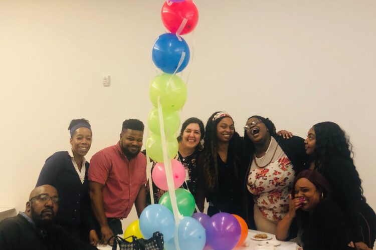 LifeStation employees gathered around a table with colorful balloons, showcasing the fun and friendly work environment promoted within LifeStation careers.