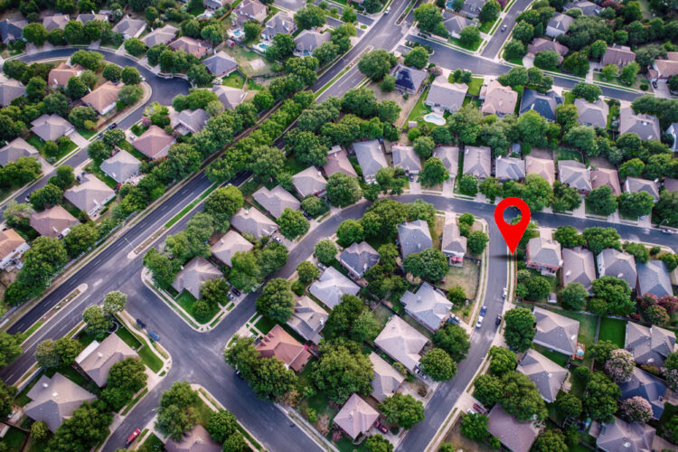Aerial view of a residential neighborhood with a red location pin, representing the availability of medical alert systems for eligible individuals at home.