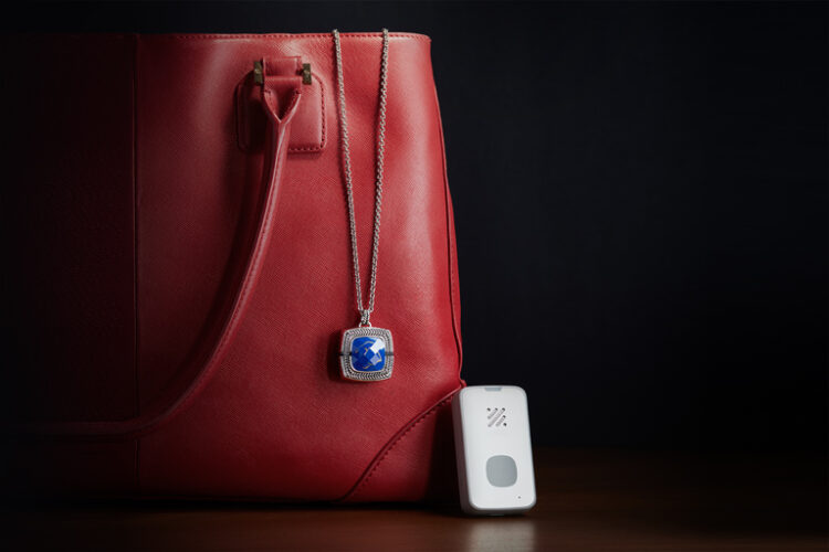 Stylish LifeStation emergency pendant necklace displayed with a red handbag and a sleek alert device, showcasing the elegance of LifeStation's luxury jewelry system for discreet safety.