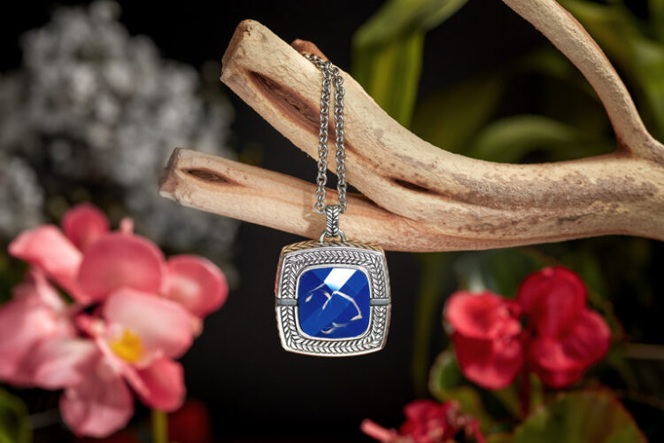 legant LifeStation emergency pendant with a blue gemstone, draped over a decorative branch, highlighting the stylish design of LifeStation's luxury jewelry safety system.