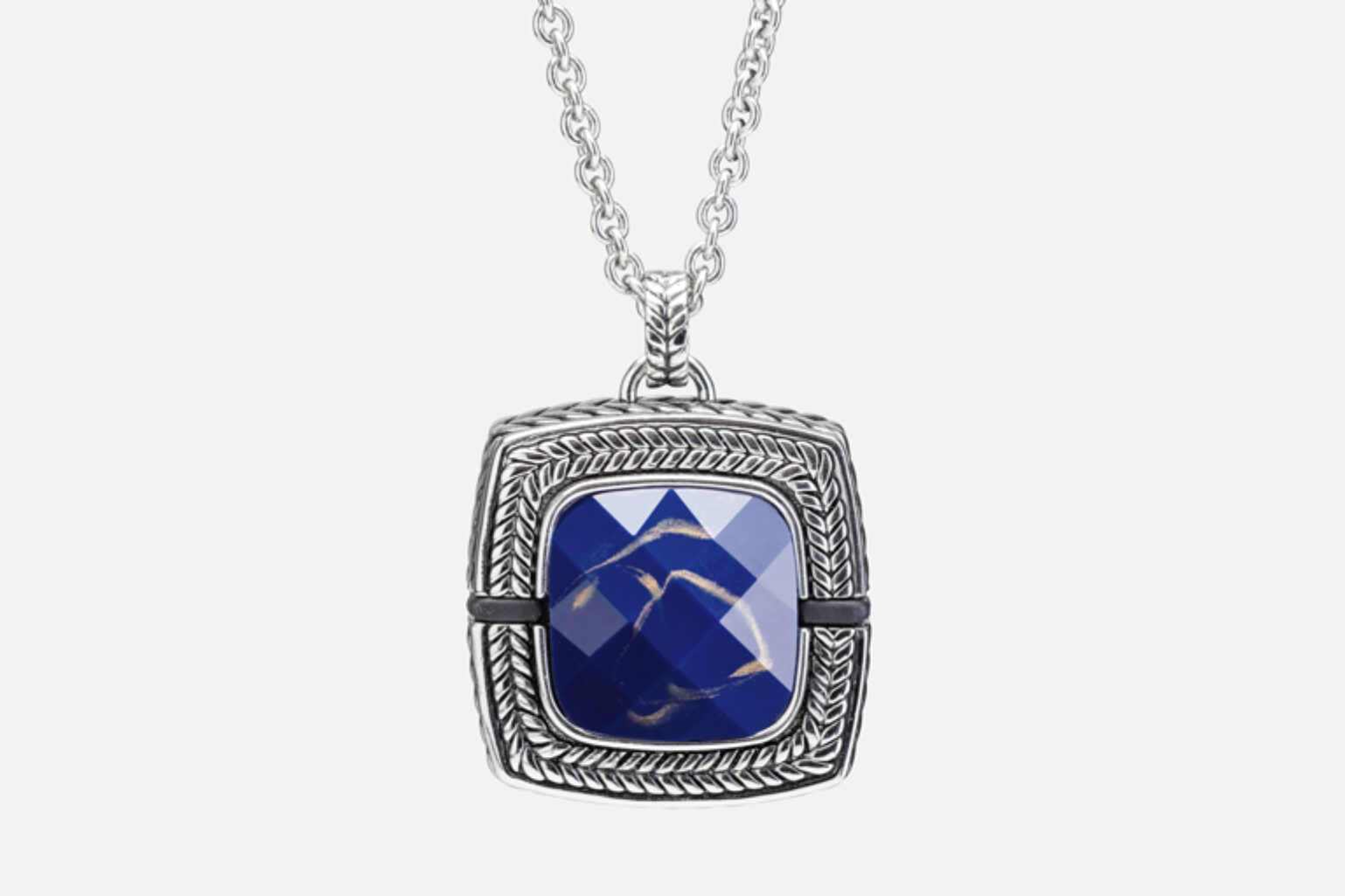 Close-up view of silver necklace pendant with a braided border and a faceted blue gemstone