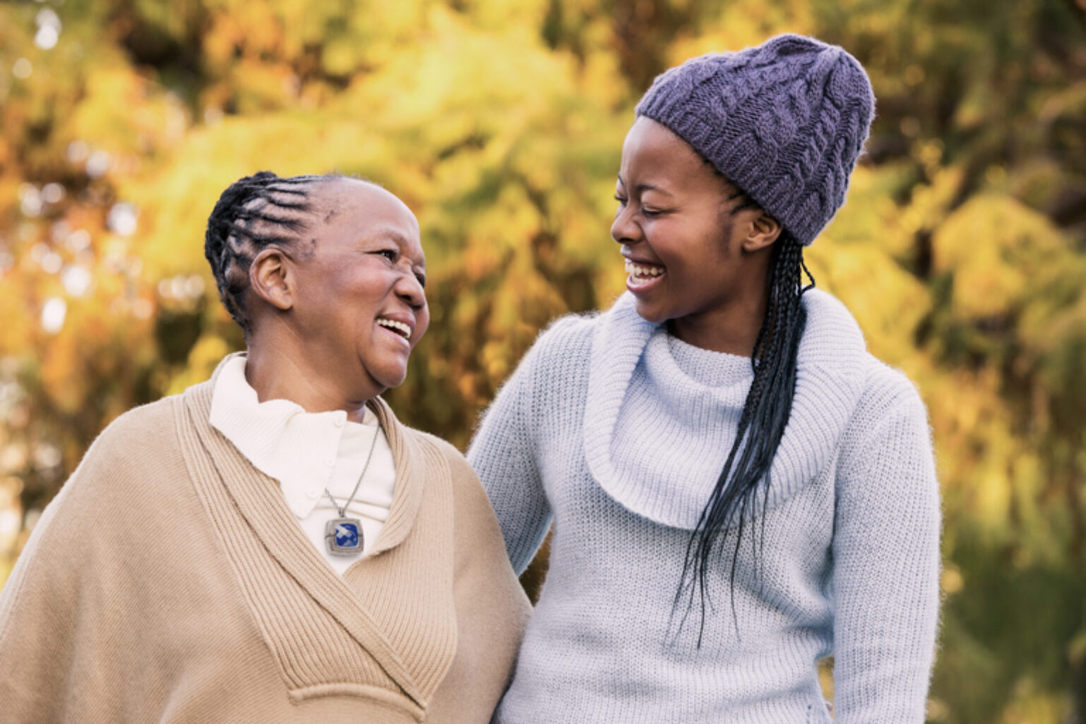 Two women smiling, one wearing a discreet medical alert pendant