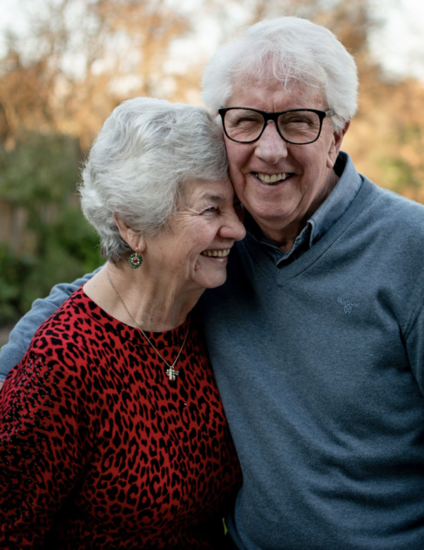 a happy elderly couple. the woman is wearing a medical alert necklace