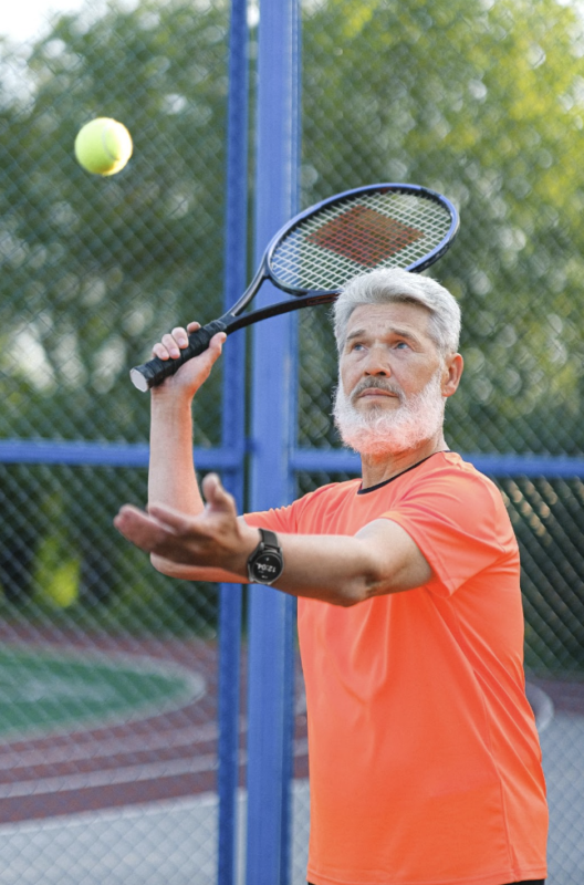 A Man playing tennis with a mobile medical alert smart watch on