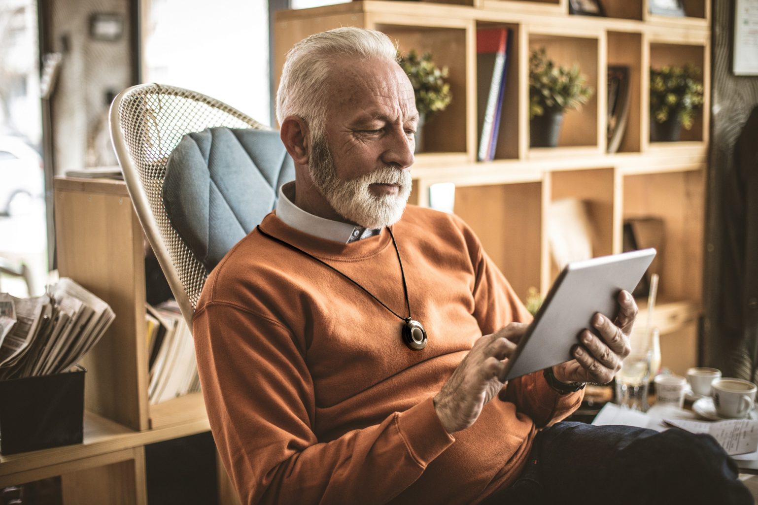 Elderly man sitting with pendant around neck