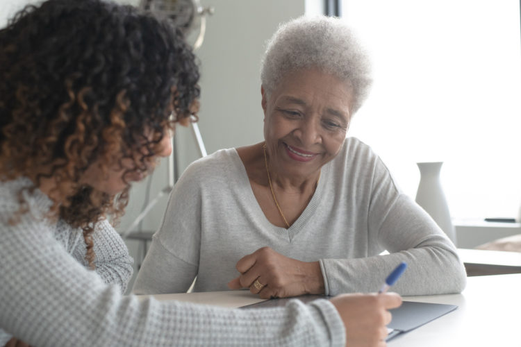 Younger woman helping an elderly lady with paper