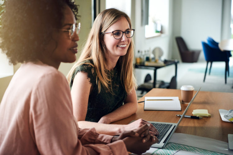 Two women working on computers and smiling