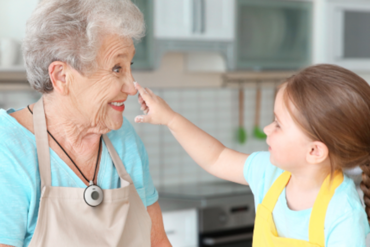 Grandmother wearing pendant and cooking with granddaughter