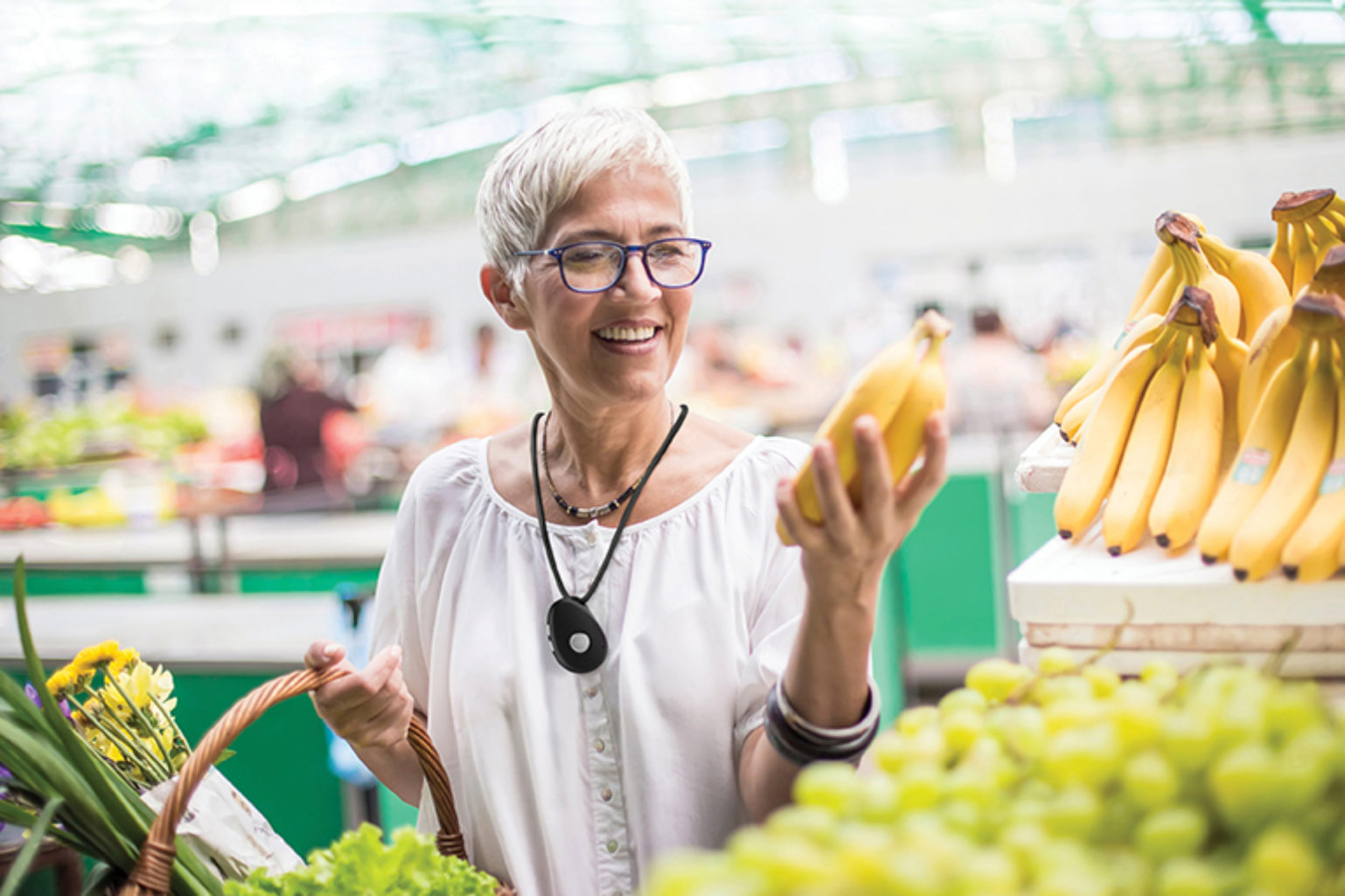 Woman at grocery store with dementia wearing a medial alert device buying bananas